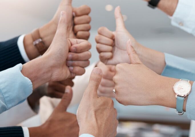 Thumbs up, business people success and hands in modern office of teamwork celebration, review and motivation. Closeup corporate group of winner employees, support and like emoji vote of goal feedback.